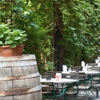 Blick vom blumengeschmückten Weinfass auf die gedeckten Tische im Gastgarten
